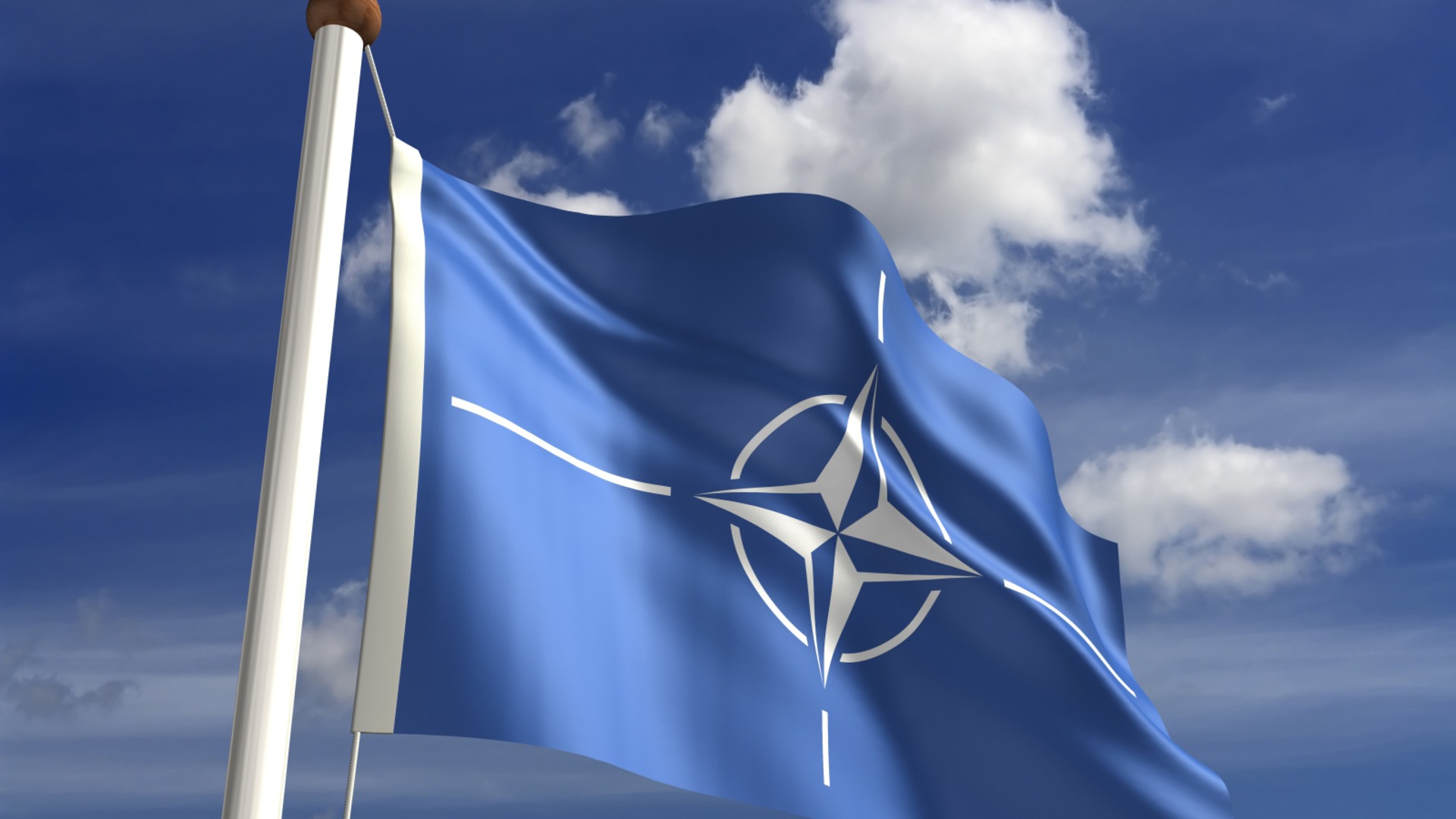 Natoflaggan vajar mot en blå himmel.
